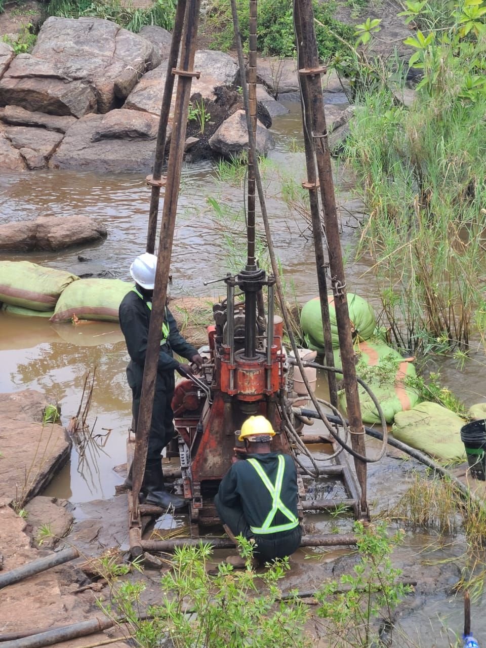Field crew operating a drilling rig within a riverbed